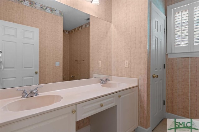 full bathroom featuring wallpapered walls, double vanity, and a sink