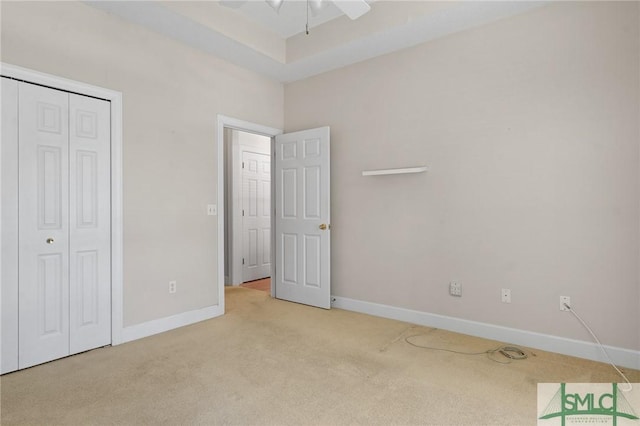 unfurnished bedroom with light colored carpet, ceiling fan, baseboards, and a closet