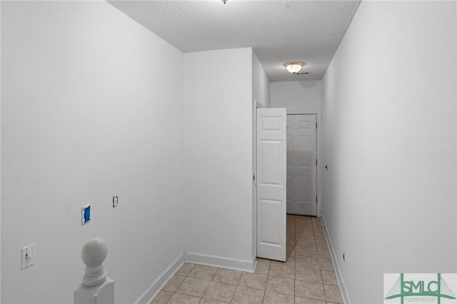 washroom featuring baseboards, light tile patterned flooring, and a textured ceiling