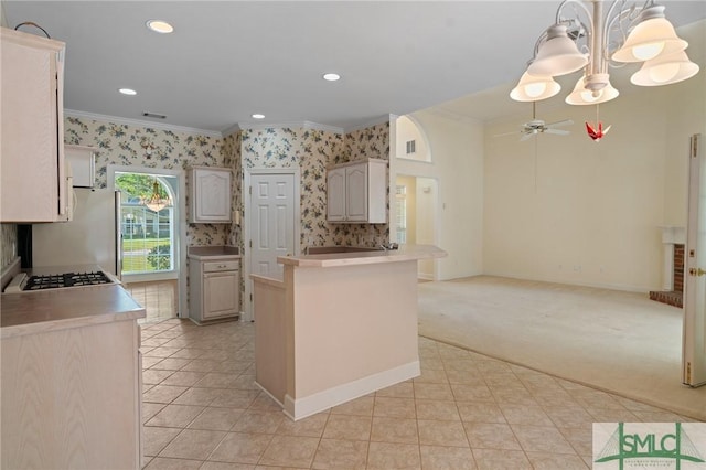 kitchen with a peninsula, open floor plan, ceiling fan with notable chandelier, wallpapered walls, and ornamental molding