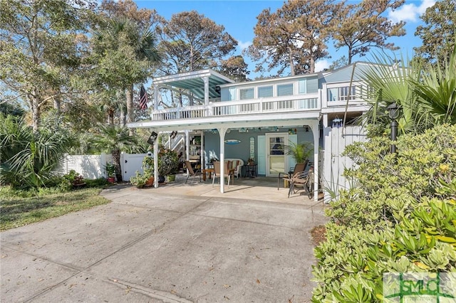 rear view of house with fence, stucco siding, a balcony, and a patio
