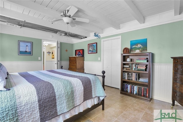 tiled bedroom with wainscoting, wooden ceiling, beam ceiling, and a closet