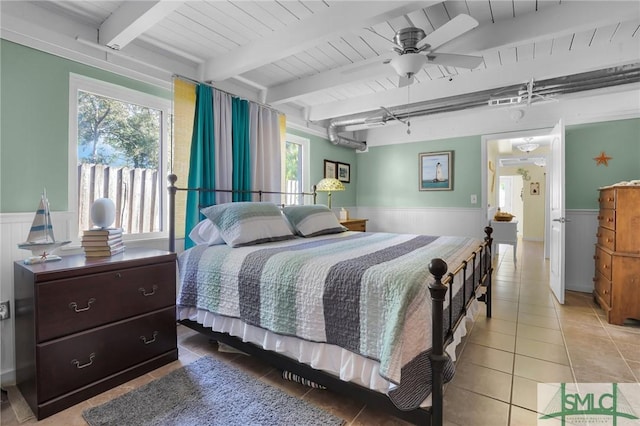bedroom featuring a wainscoted wall, multiple windows, and light tile patterned floors