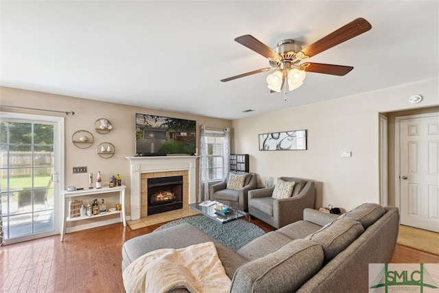 living room with a fireplace, wood-type flooring, and ceiling fan