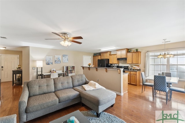 living room featuring hardwood / wood-style flooring and ceiling fan with notable chandelier