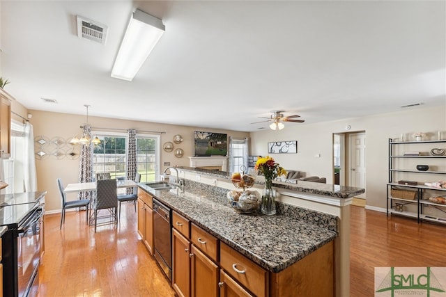 kitchen featuring light hardwood / wood-style floors, decorative light fixtures, dark stone countertops, and stainless steel dishwasher