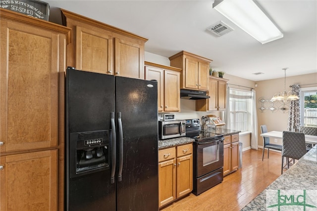 kitchen with stone countertops, black appliances, decorative light fixtures, an inviting chandelier, and light wood-type flooring