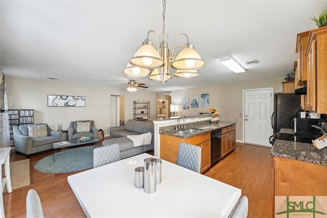 dining room featuring sink, light wood-type flooring, and ceiling fan with notable chandelier