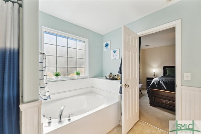 bathroom with a tub to relax in and tile patterned flooring