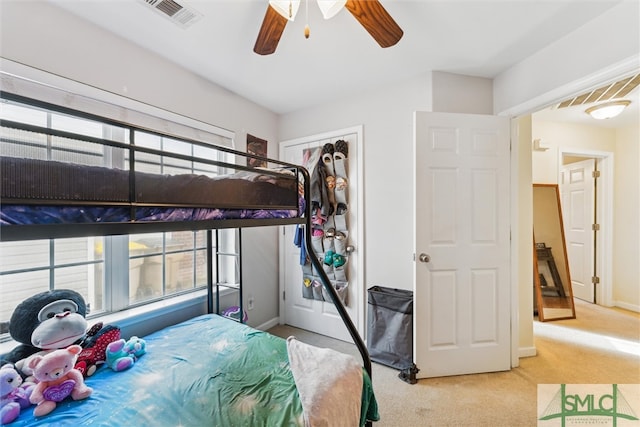 bedroom with a closet, light colored carpet, and ceiling fan