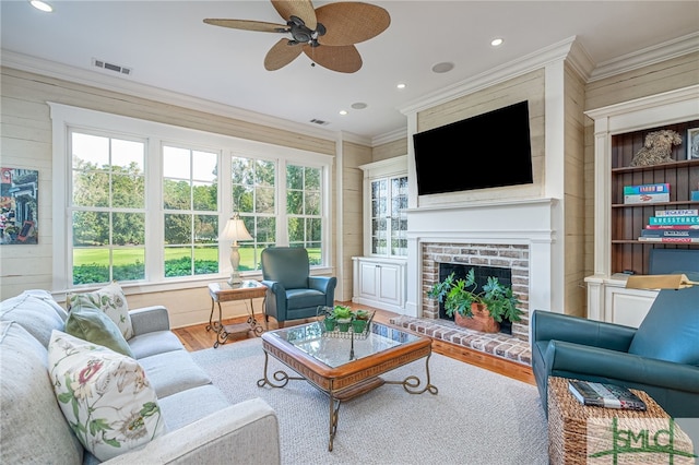 living room featuring hardwood / wood-style floors, a fireplace, crown molding, and ceiling fan