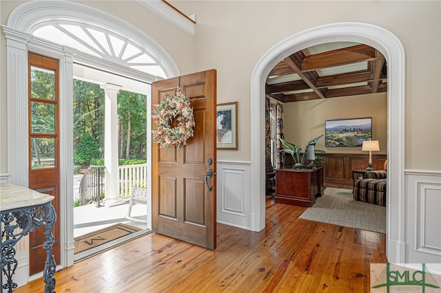 entrance foyer with ornamental molding, beamed ceiling, coffered ceiling, and light wood-type flooring