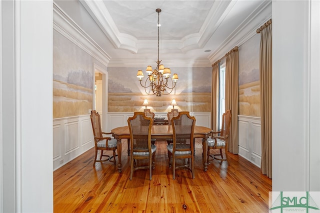 dining area with a notable chandelier, a tray ceiling, light wood-type flooring, and crown molding