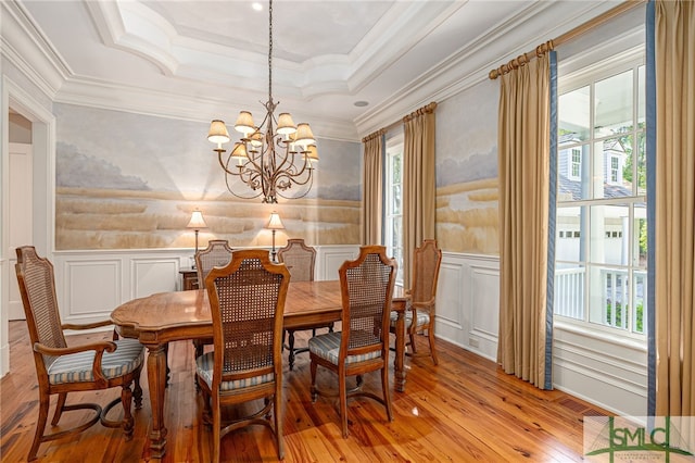 dining space with an inviting chandelier, crown molding, light wood-type flooring, and plenty of natural light