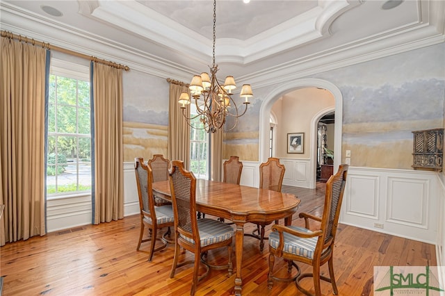 dining room with ornamental molding, light hardwood / wood-style floors, and a raised ceiling