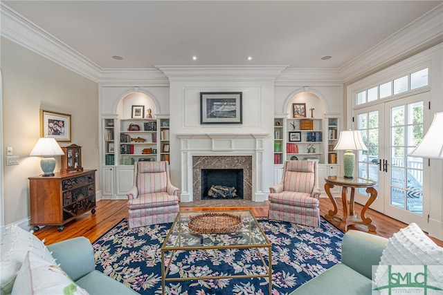 living room featuring ornamental molding, french doors, a fireplace, and hardwood / wood-style flooring