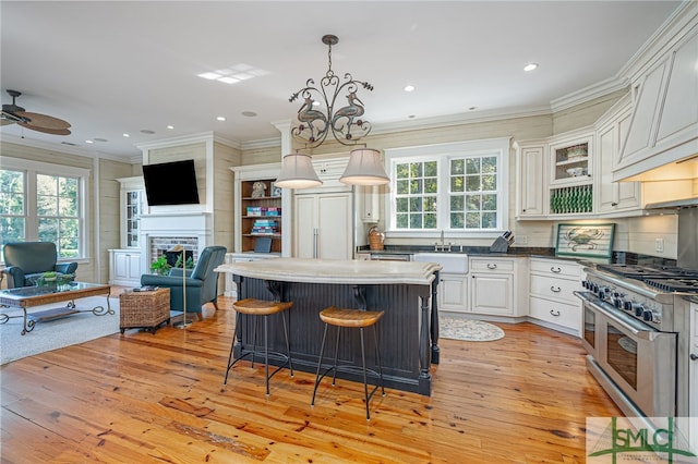 kitchen featuring white cabinets, hanging light fixtures, light wood-type flooring, and double oven range