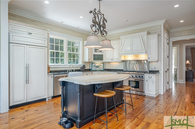 kitchen featuring white cabinets, light wood-type flooring, sink, a center island, and high end appliances