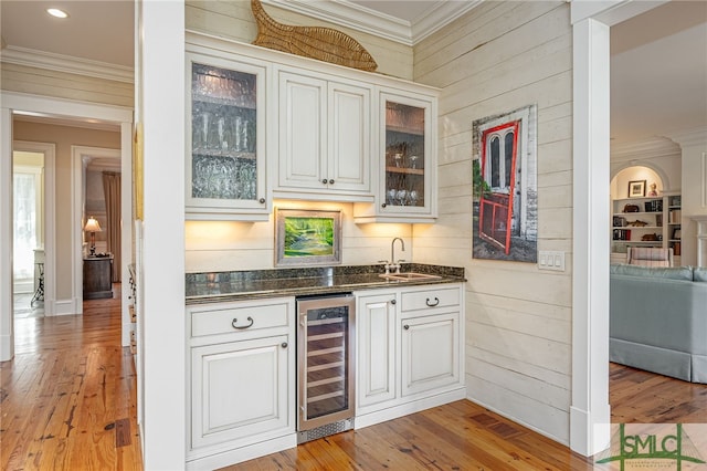 bar with white cabinetry, ornamental molding, light hardwood / wood-style flooring, and beverage cooler