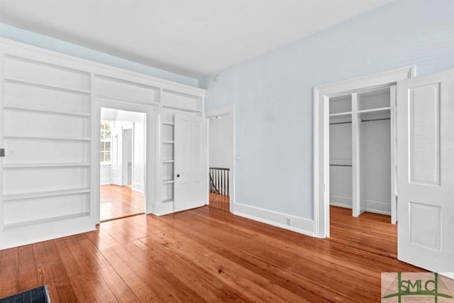 117 W Gaston St, Savannah, GA 31401 - unfurnished bedroom featuring baseboards, a walk in closet, hardwood / wood-style flooring, and a closet