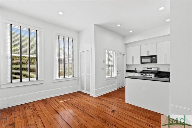 117 W Gaston St, Savannah, GA 31401 - kitchen with black microwave, dark countertops, baseboards, dark wood-style floors, and stainless steel range with gas stovetop