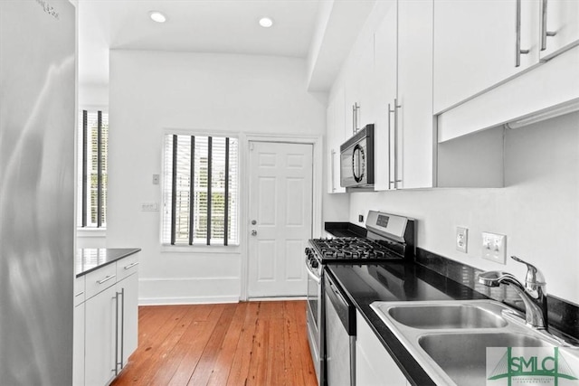 117 W Gaston St, Savannah, GA 31401 - kitchen featuring a sink, light wood-style flooring, appliances with stainless steel finishes, and dark countertops