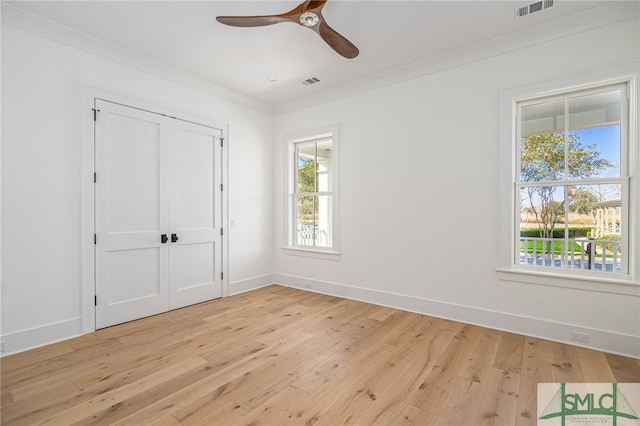 unfurnished bedroom featuring multiple windows, ornamental molding, and light wood-type flooring