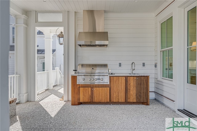 kitchen with ornate columns, sink, and wall chimney range hood