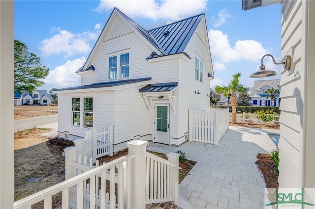 rear view of house featuring metal roof, a standing seam roof, a patio, and fence