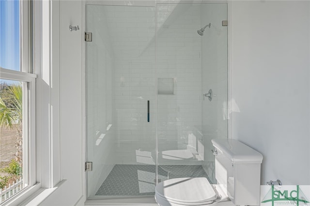 bathroom with a shower with shower door and toilet