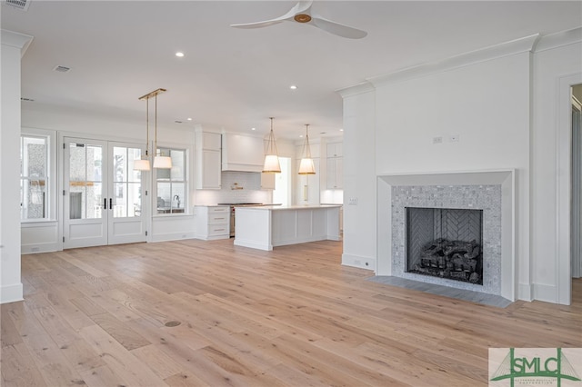 unfurnished living room featuring sink, french doors, ceiling fan, and light wood-type flooring