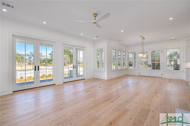 unfurnished living room with french doors, ornamental molding, a healthy amount of sunlight, and light wood-type flooring