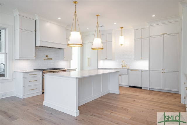 kitchen featuring pendant lighting, high end stainless steel range, custom range hood, and white cabinets