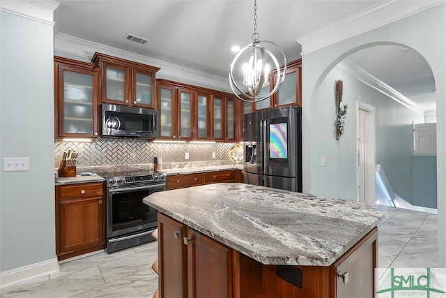 kitchen with a kitchen island, appliances with stainless steel finishes, light stone countertops, ornamental molding, and pendant lighting