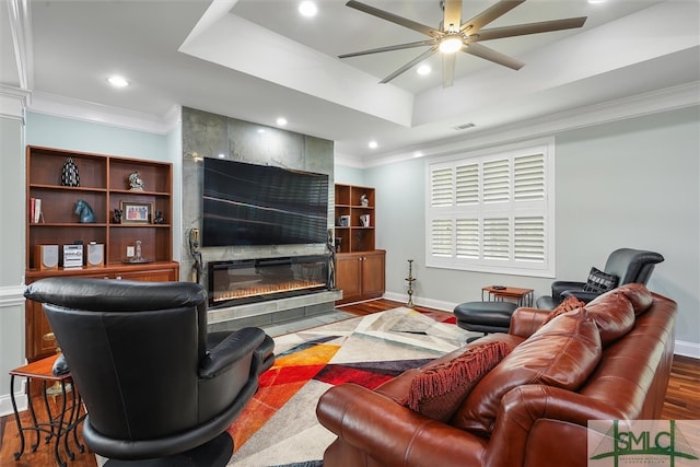 living room with a large fireplace, hardwood / wood-style flooring, crown molding, and ceiling fan