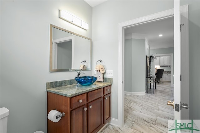 bathroom featuring toilet, ornamental molding, and vanity