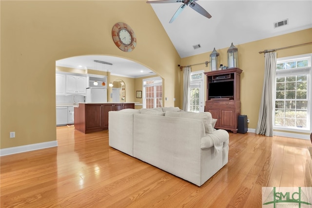 living room featuring light hardwood / wood-style flooring, high vaulted ceiling, and ceiling fan