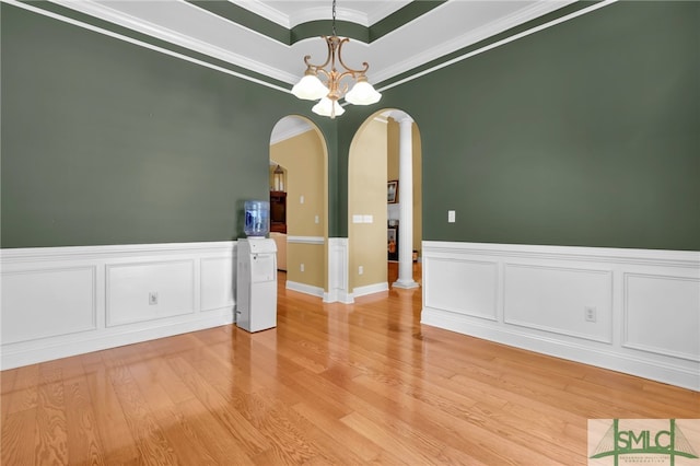 unfurnished room with light hardwood / wood-style flooring, crown molding, decorative columns, a raised ceiling, and a chandelier