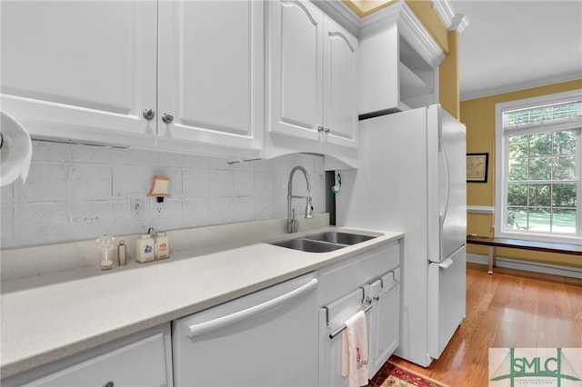 kitchen with white appliances, sink, backsplash, light hardwood / wood-style floors, and white cabinets