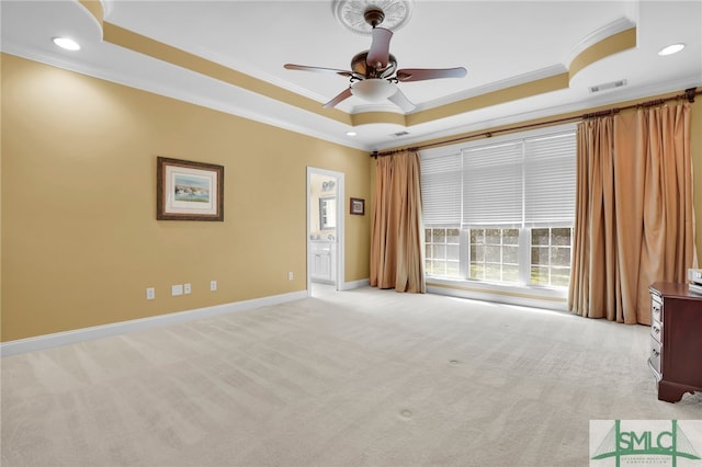 empty room with crown molding, light carpet, a tray ceiling, and ceiling fan