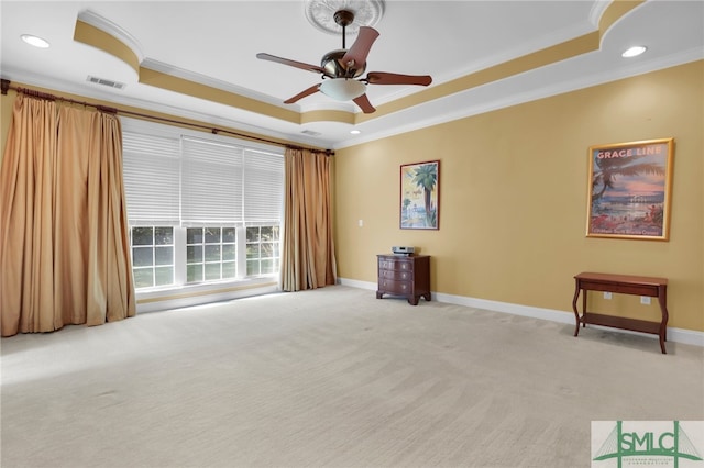 carpeted spare room with crown molding, a tray ceiling, and ceiling fan