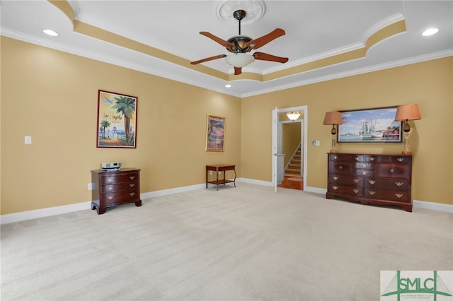 interior space featuring ornamental molding, ceiling fan, light colored carpet, and a raised ceiling