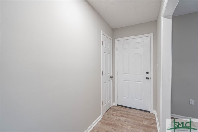 doorway to outside with a textured ceiling and light wood-type flooring