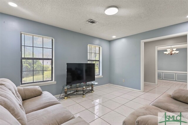 living room with a notable chandelier, a healthy amount of sunlight, and light tile patterned flooring