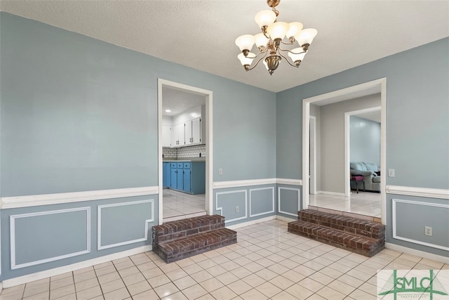 interior space featuring a textured ceiling, light tile patterned floors, and an inviting chandelier