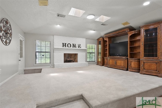 unfurnished living room featuring a brick fireplace, a textured ceiling, lofted ceiling with skylight, and carpet