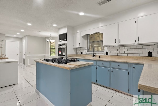 kitchen with backsplash, white cabinets, stainless steel appliances, and a center island