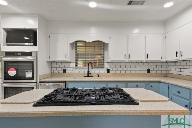 kitchen with stainless steel appliances, sink, blue cabinetry, and white cabinets