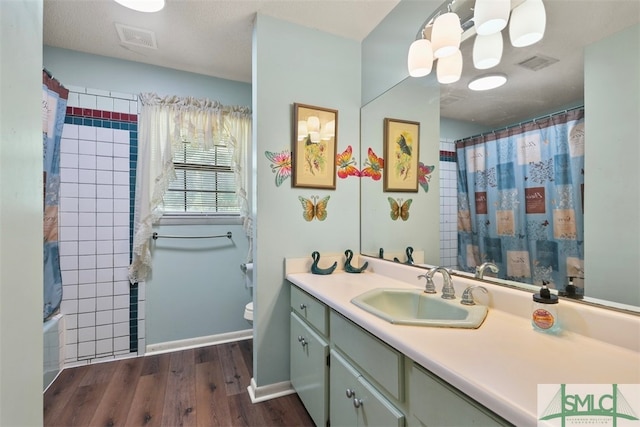 full bathroom featuring hardwood / wood-style flooring, shower / tub combo with curtain, vanity, and toilet