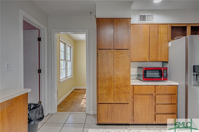 kitchen with stainless steel appliances, ornamental molding, and light tile patterned floors